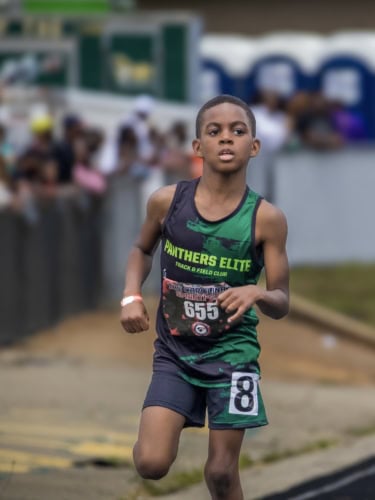 Young athlete running in a track race wearing Panthers Elite gear.