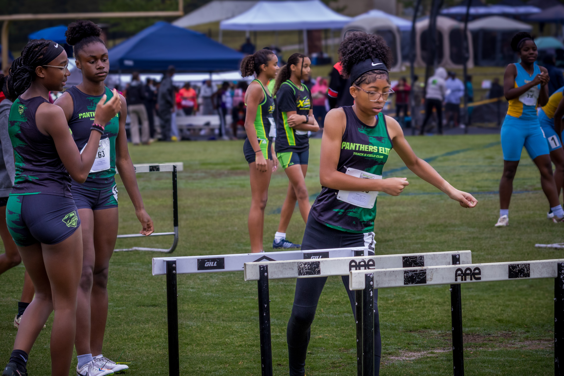 Athletes from Panthers Elite Track & Field Club warming up and preparing for hurdles race at an outd.
