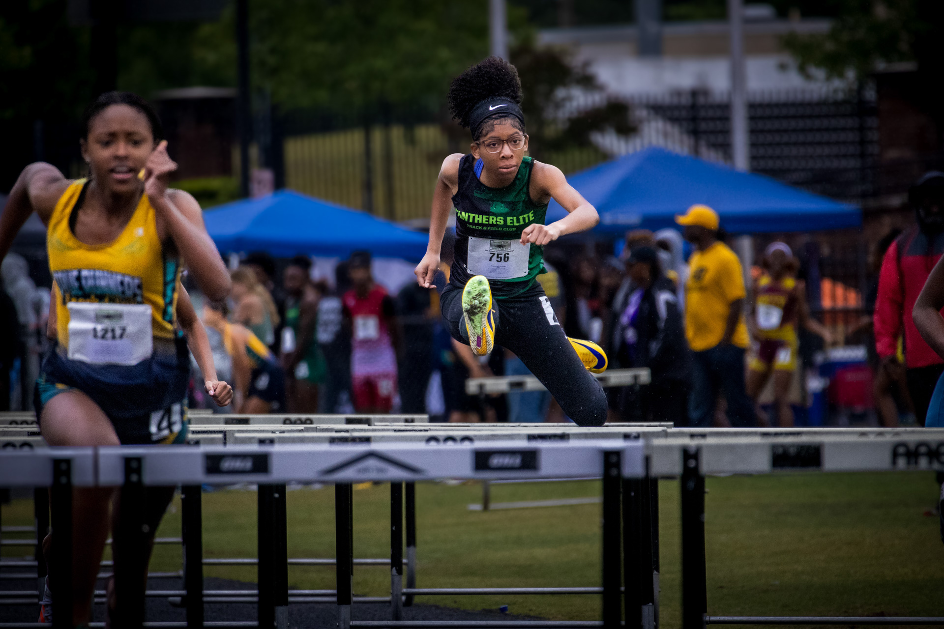 Female athlete jumping over hurdles at Panthers Elite Track & Field meet.