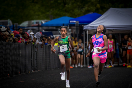 Two young female athletes competing in a track race at Panthers Elite Track & Field Club event.