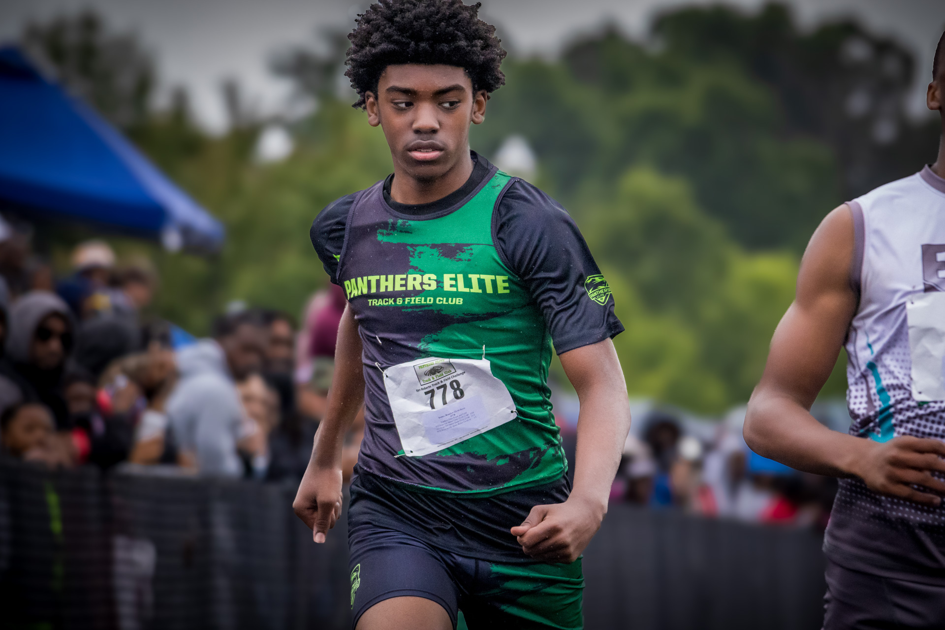 Young male athlete running in a track race wearing Panthers Elite uniform.