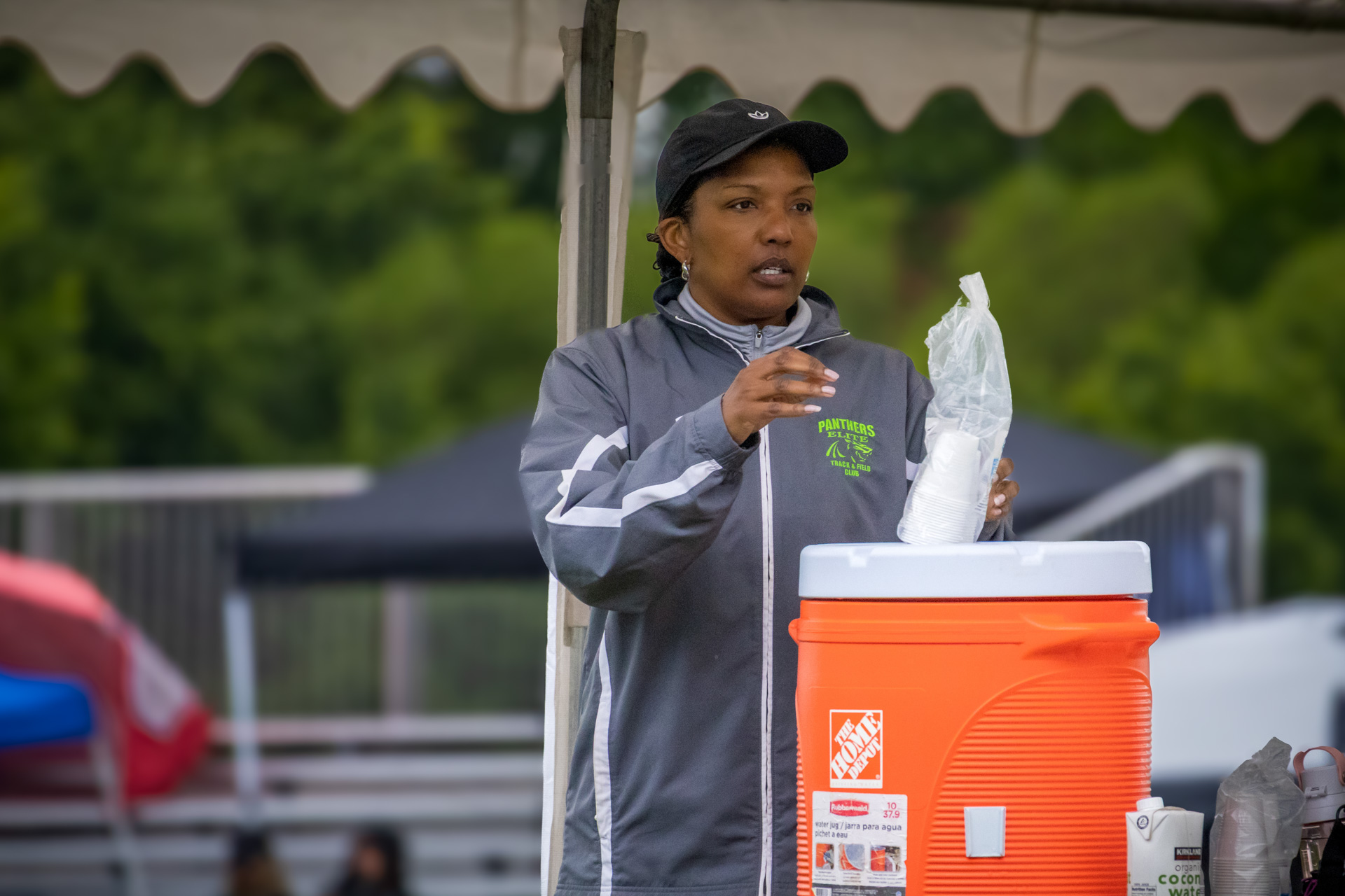 Female Panthers Elite coach preparing hydration at outdoor track meet.