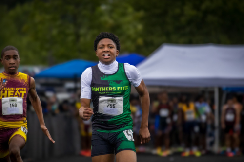 Young male athlete running in a track race during a Panthers Elite meet.