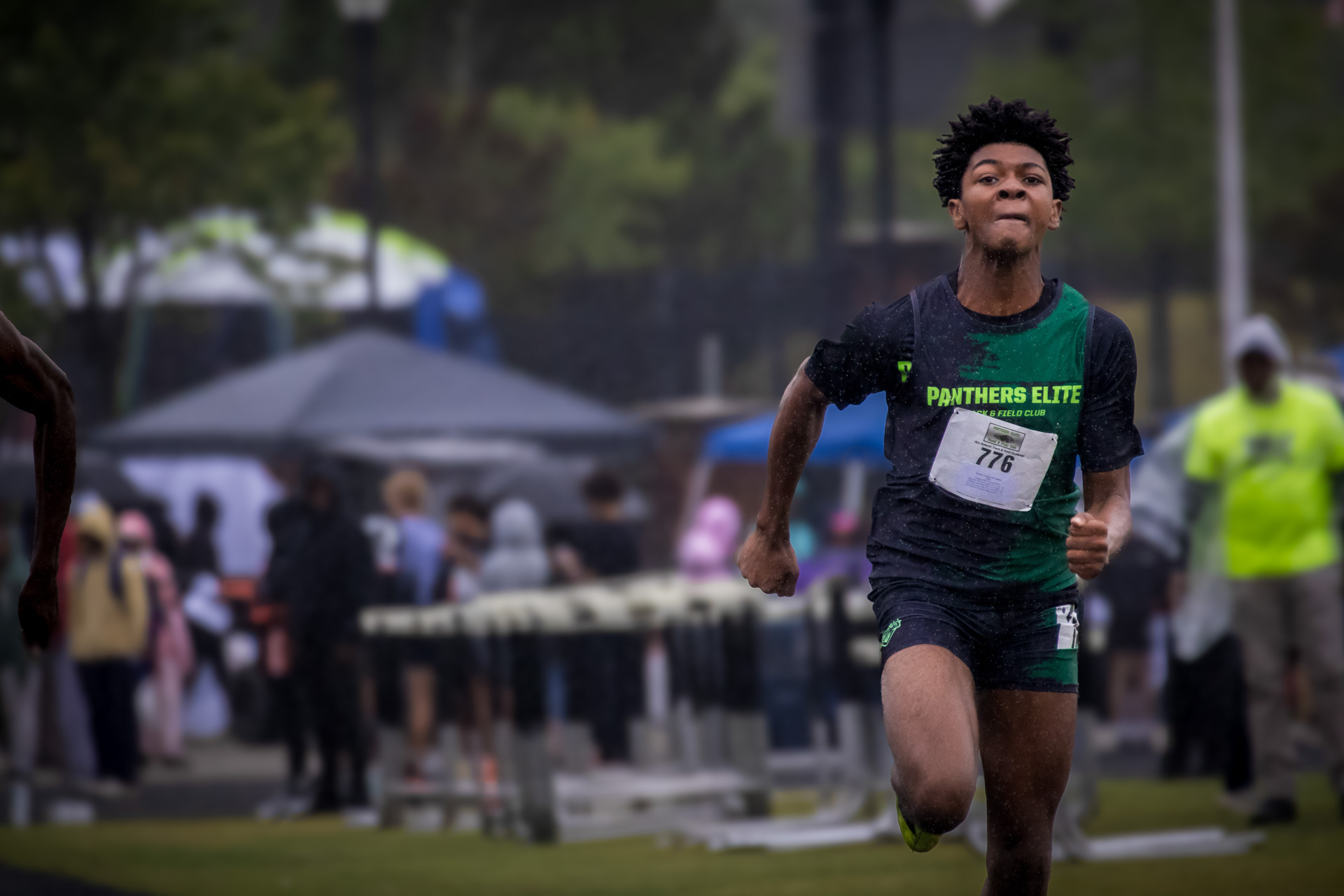 Young male athlete sprinting during a track meet, wearing a Panthers Elite uniform with a race bib.