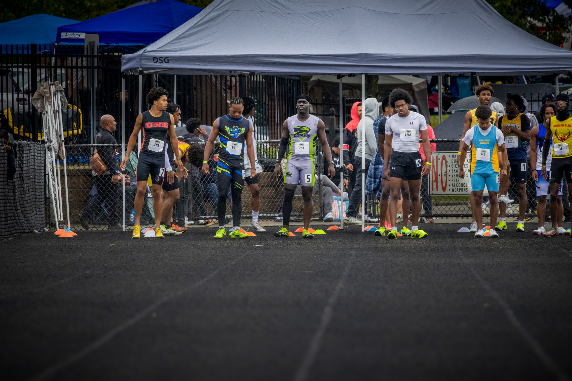 Athletes lined up at the starting line during a track meet, ready to compete in a sprint race at a P.