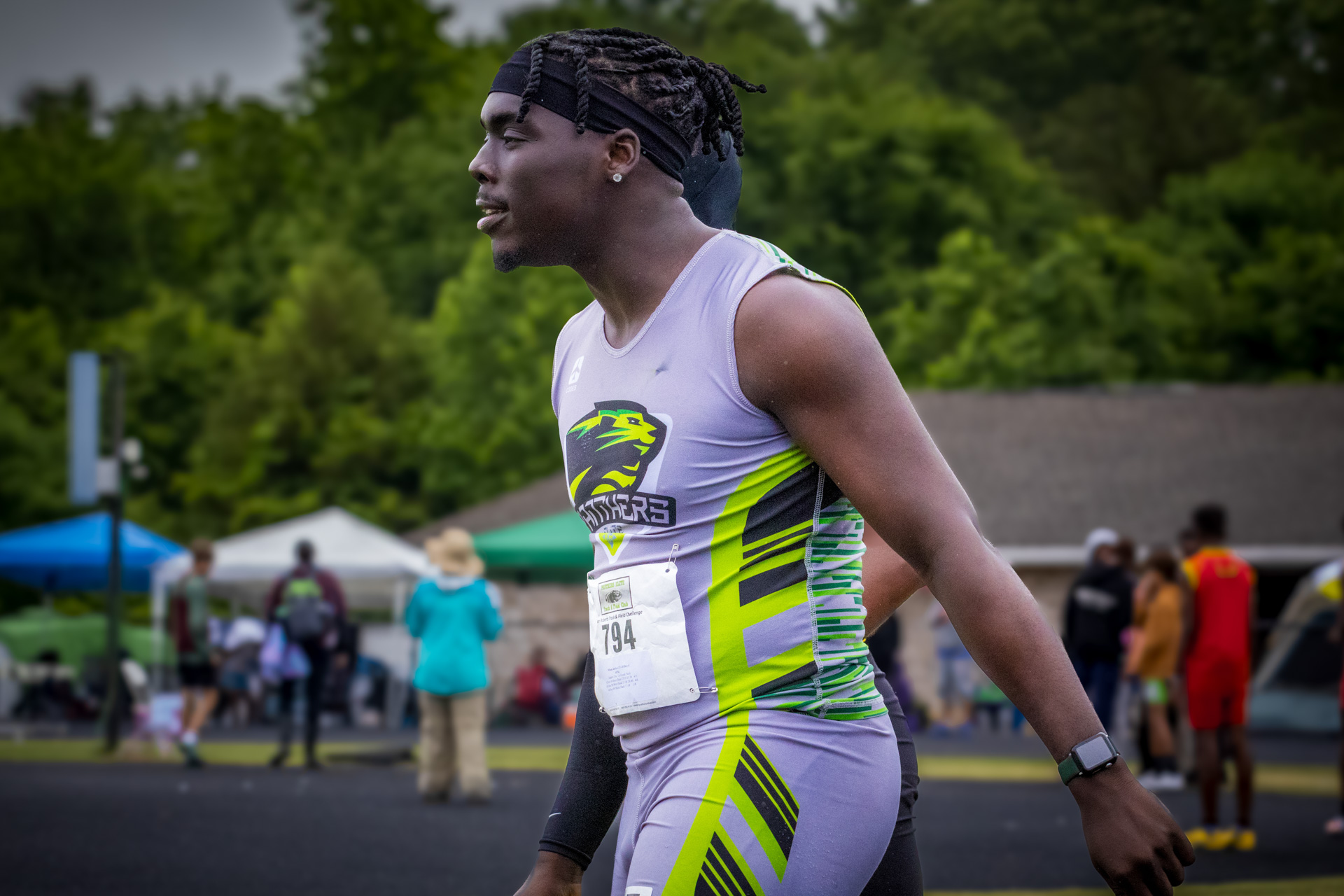 Female track athlete in Panthers Elite uniform at outdoor meet.