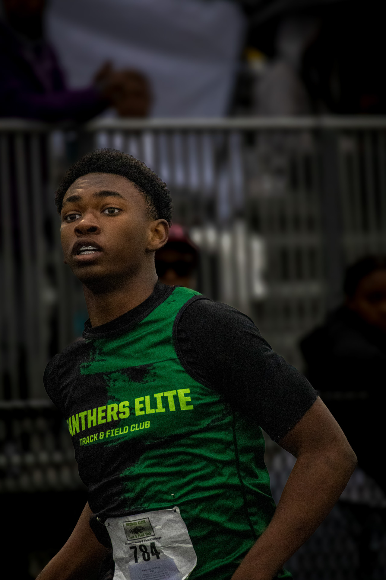 Young athlete in green Panthers Elite uniform at track event.