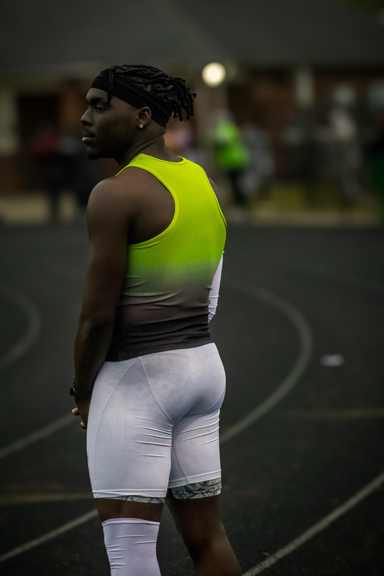 Young male track athlete in neon yellow and white uniform on the track.