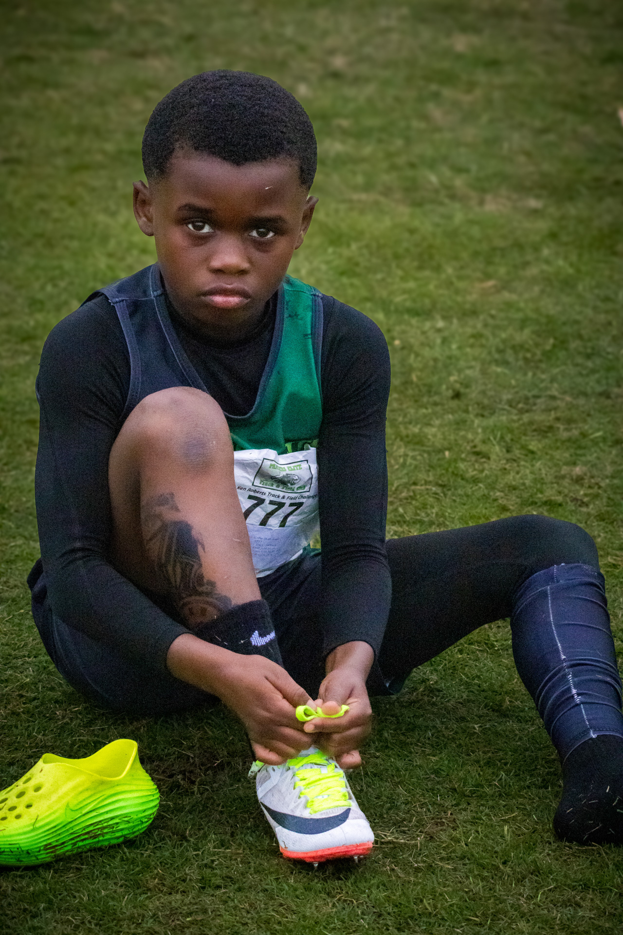 Young athlete tying shoelaces on the grass field.