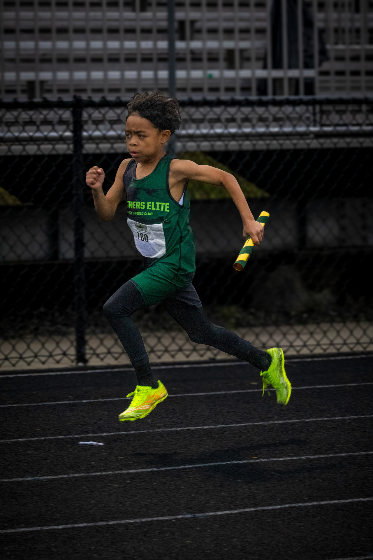 Young athlete running on track with baton during a race.