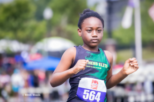 Young female athlete running in a track event, wearing a Panthers Elite uniform and bib number 564.