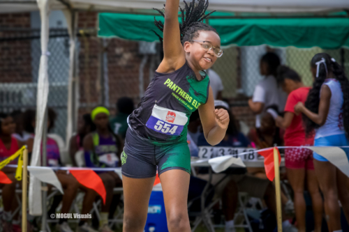 Young female athlete smiling and celebrating after a race at a track meet.