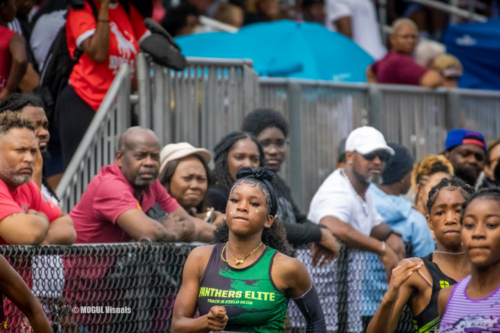 Athletes competing at Panthers Elite Track & Field Club meet, surrounded by spectators and supporter.