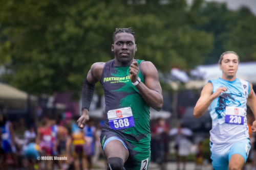 Male track athlete running in a race, wearing a green and black uniform with number 588.