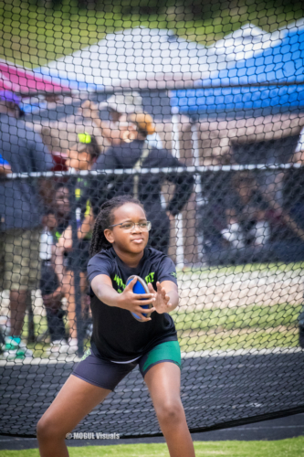 Young female athlete preparing to catch a shot put during a track meet.