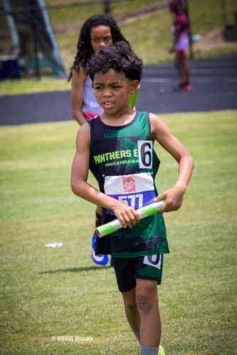 Young athlete holding a relay baton during a track meet at Panthers Elite.