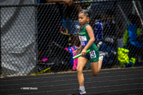 An athlete from Panthers Elite Track & Field Club running on the track during a meet, holding a rela.