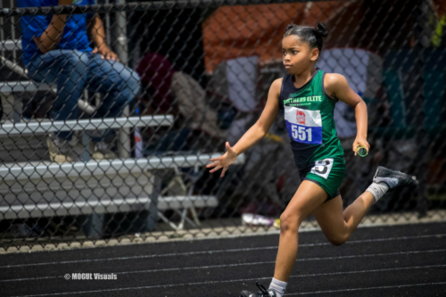 Young female athlete sprinting on the track during a meet.