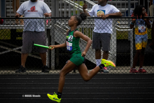 Young female athlete sprinting on track during a competition.