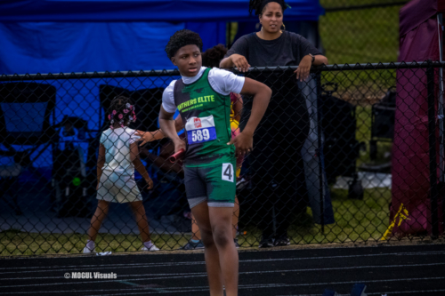 Athlete at Panthers Elite Track & Field Club preparing for a race, standing near the track with a co.