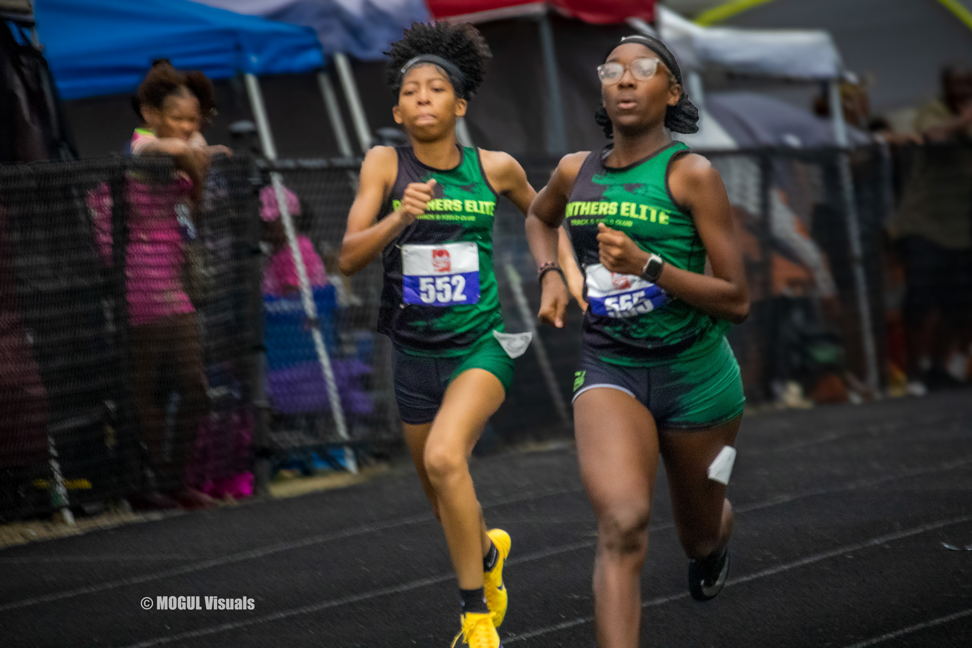 Two young female athletes running on a track during a race at Panthers Elite Track & Field Club.