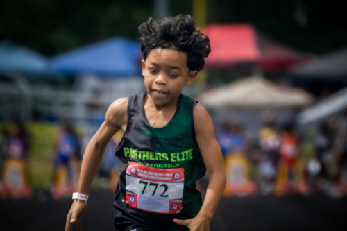 Young male athlete running at District Qualifier 2026 event.