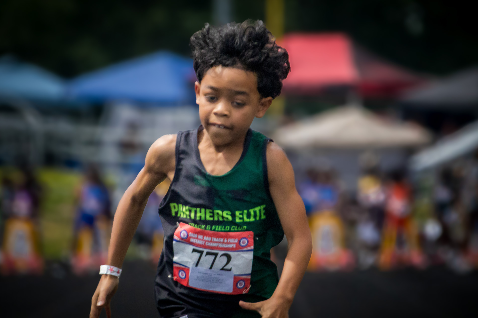 Young male athlete running at District Qualifier 2026 event.