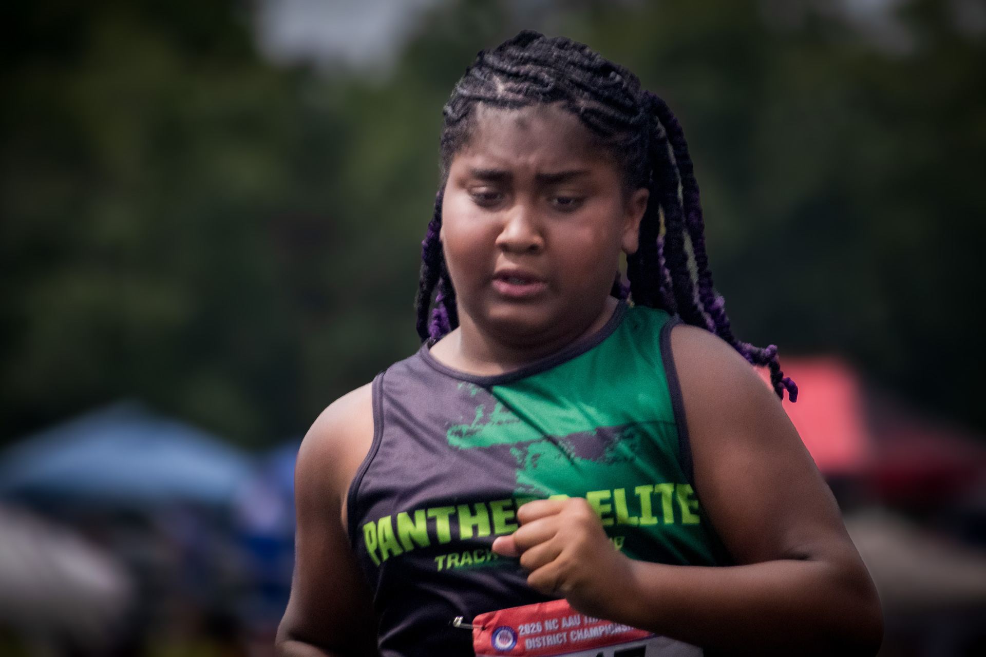 Young female athlete running at District Qualifier 2026 event.
