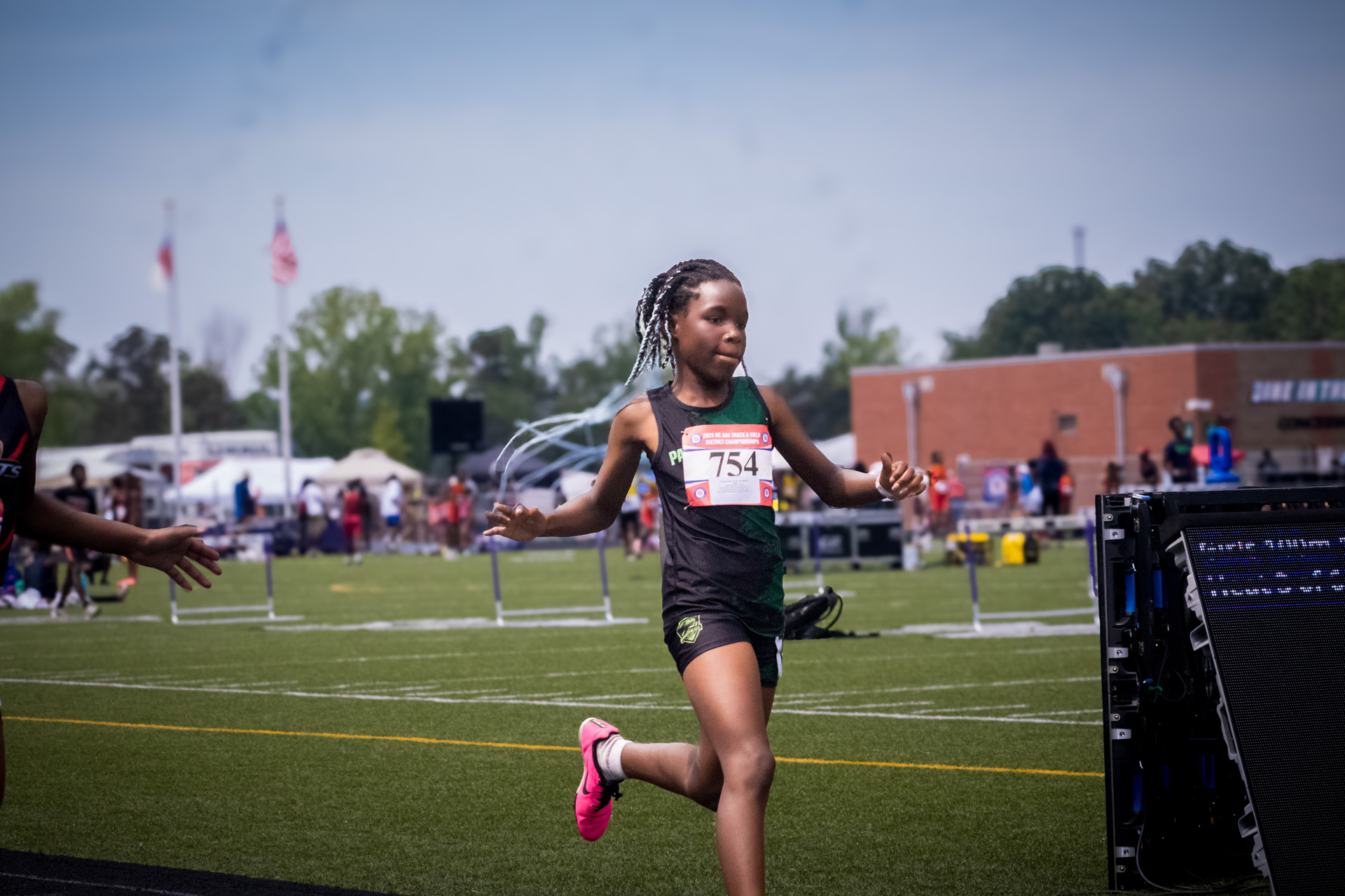 Young female athlete running in a track and field event at a district qualifier.