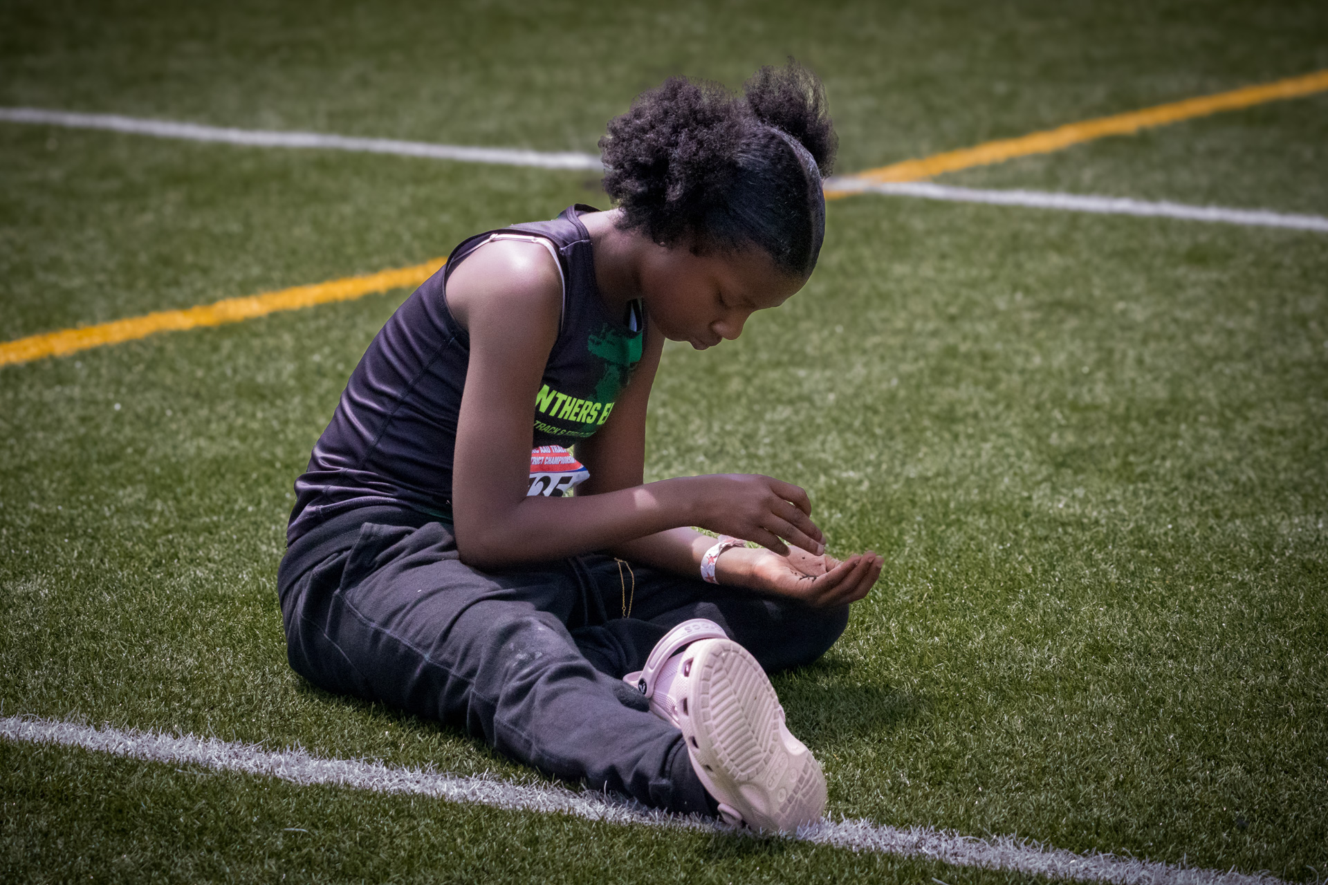 Young female athlete sitting on the field after a race or practice session.