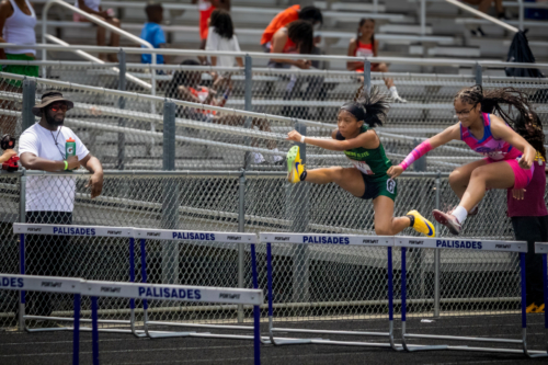 Young female athletes competing in hurdles at District Qualifier 2026.