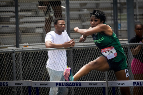 Female track athlete clearing hurdle at District Qualifier 2026.