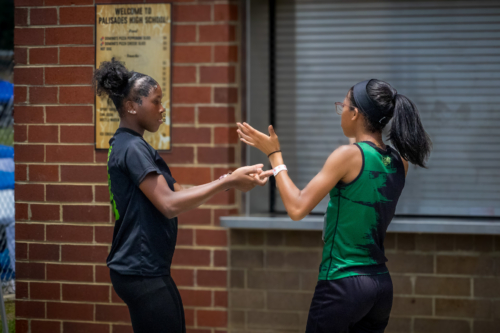 Two female athletes from Panthers Elite Track & Field Club talking outside school.