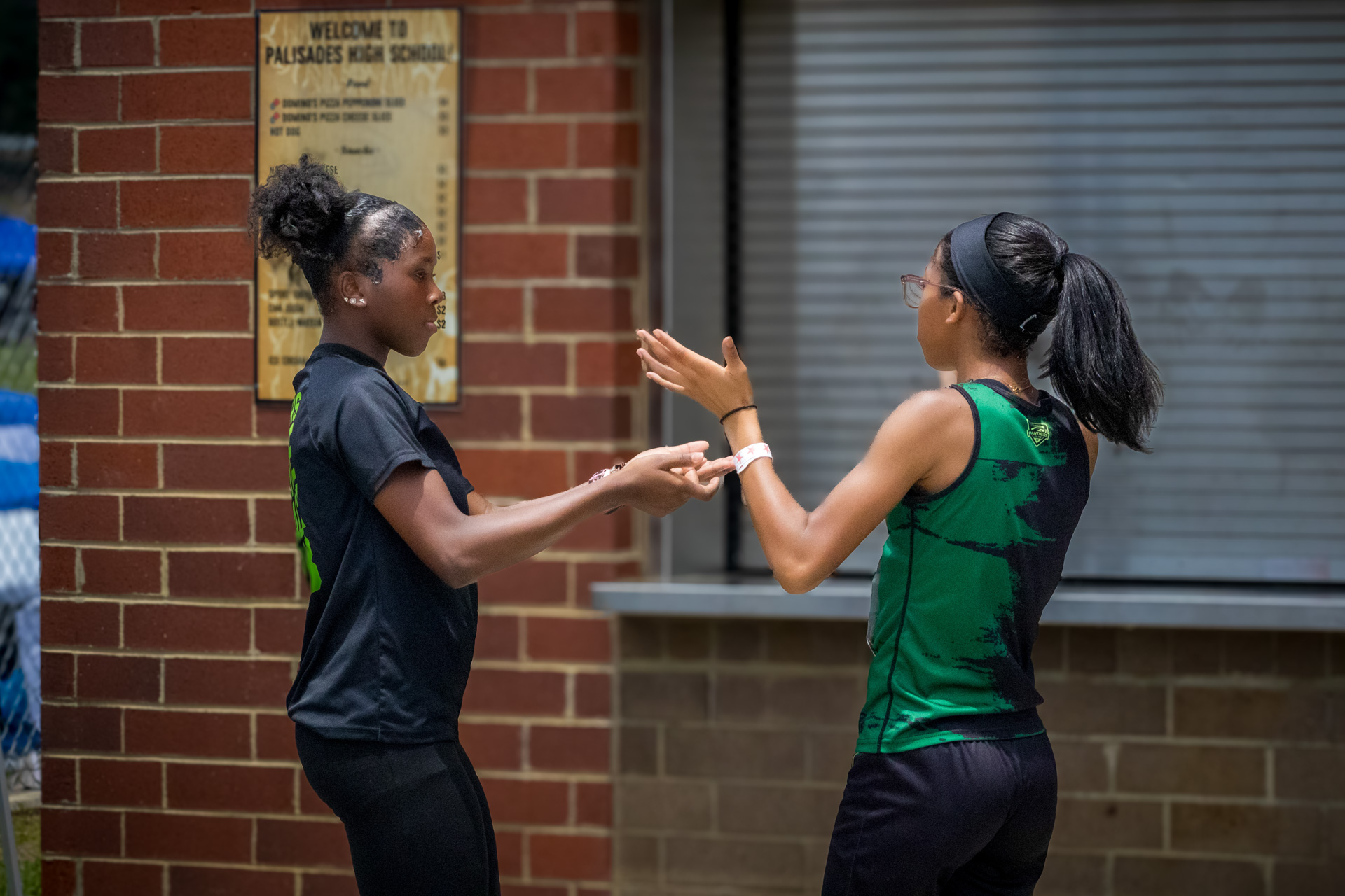 Two female athletes from Panthers Elite Track & Field Club talking outside school.
