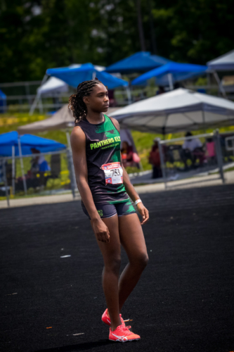 Young female athlete in Panthers Elite uniform at district track meet.