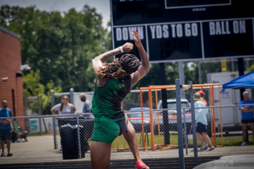 Female athlete jumping during a track and field event at district qualifier.