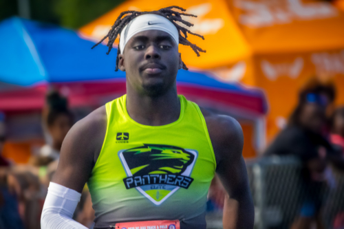 Panthers Elite track athlete in neon green uniform at district qualifier.