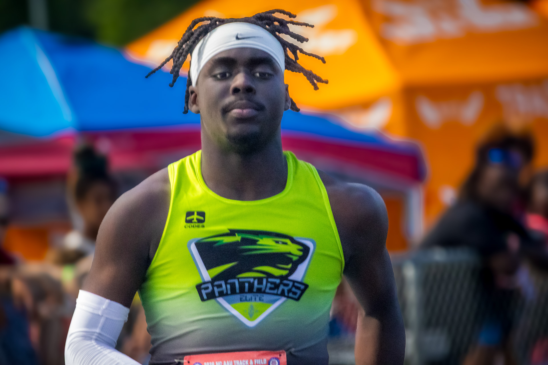 Panthers Elite track athlete in neon green uniform at district qualifier.