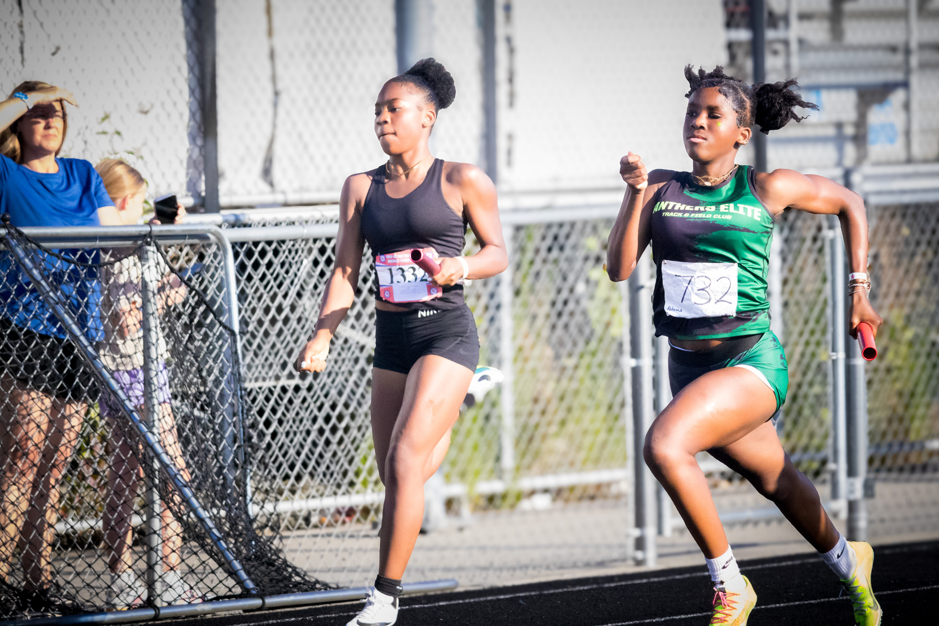 Two female athletes competing in a track race at a district qualifier event.