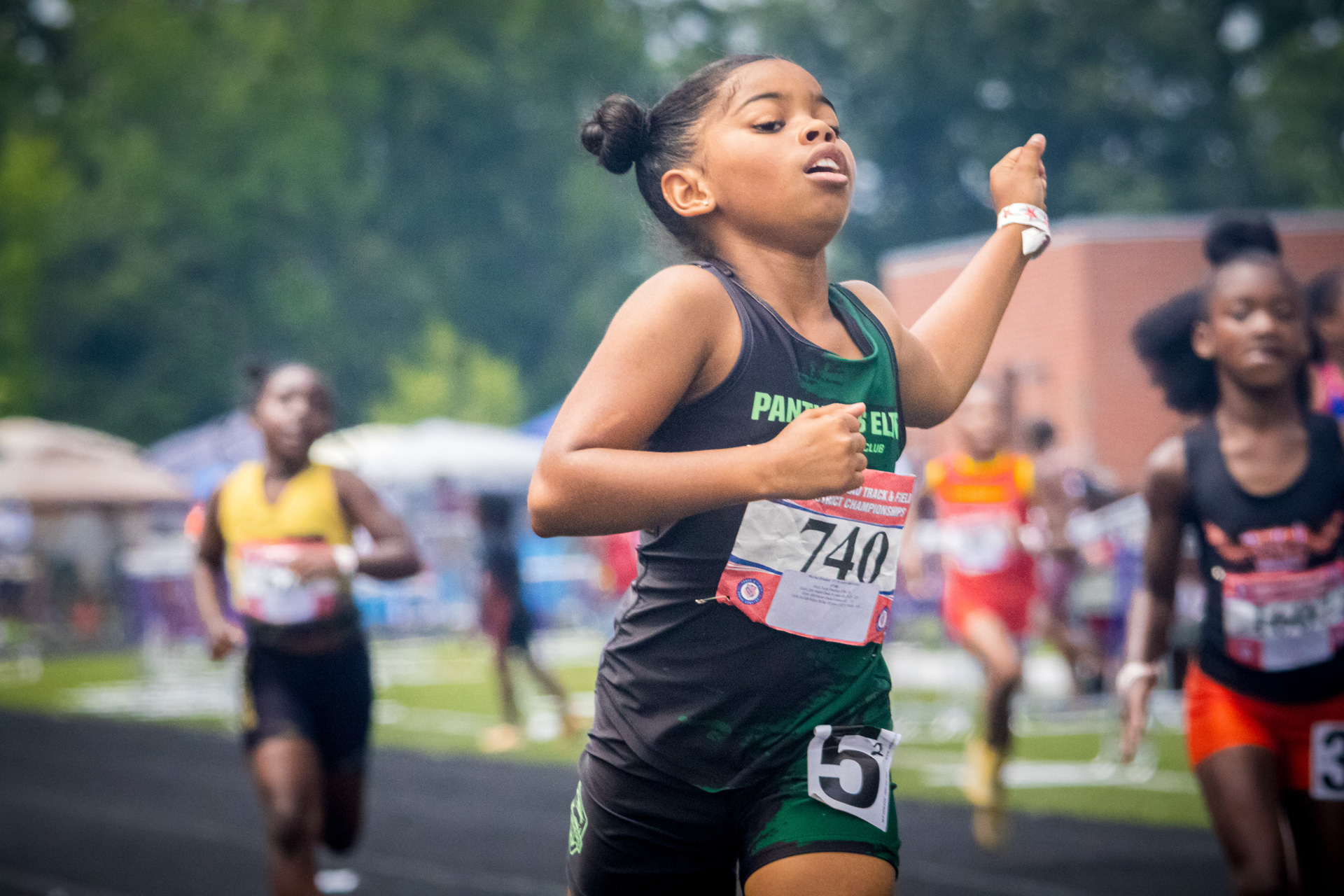 Young female athlete running in a track race at district qualifier 2026.