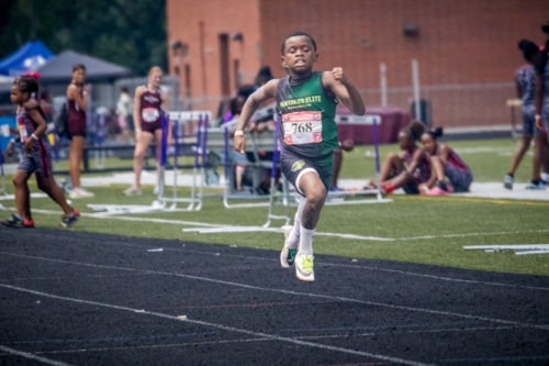 Young male athlete competing in a track and field race at district qualifier 2026.