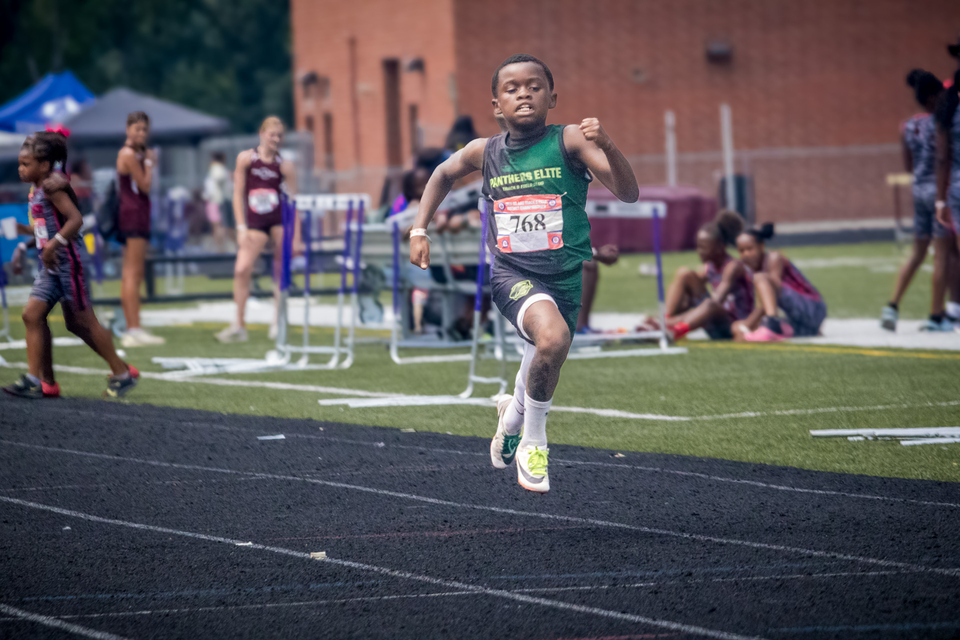 Young male athlete competing in a track and field race at district qualifier 2026.