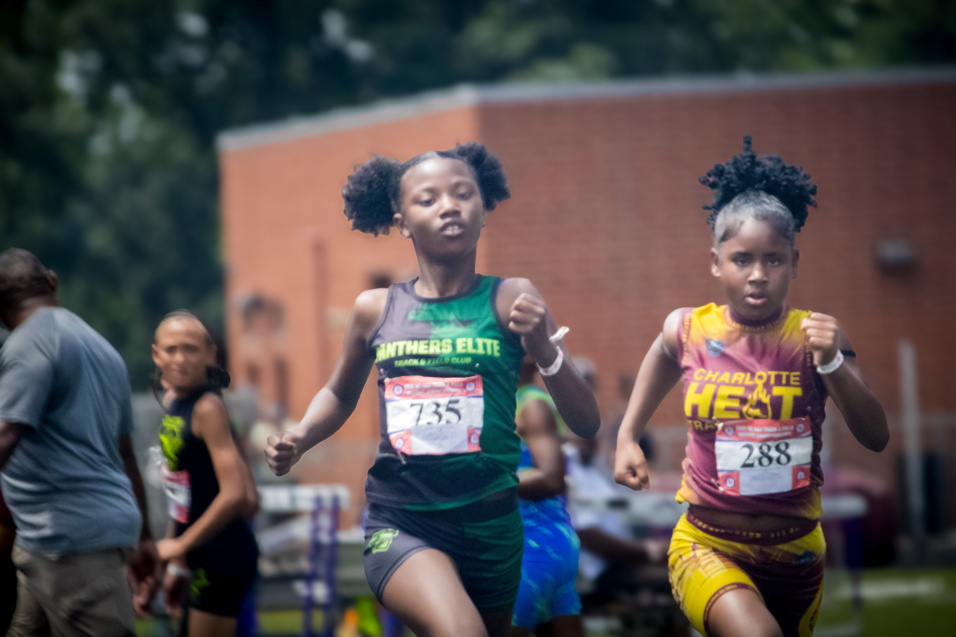 Young female runners competing in a track race at a district qualifier event.