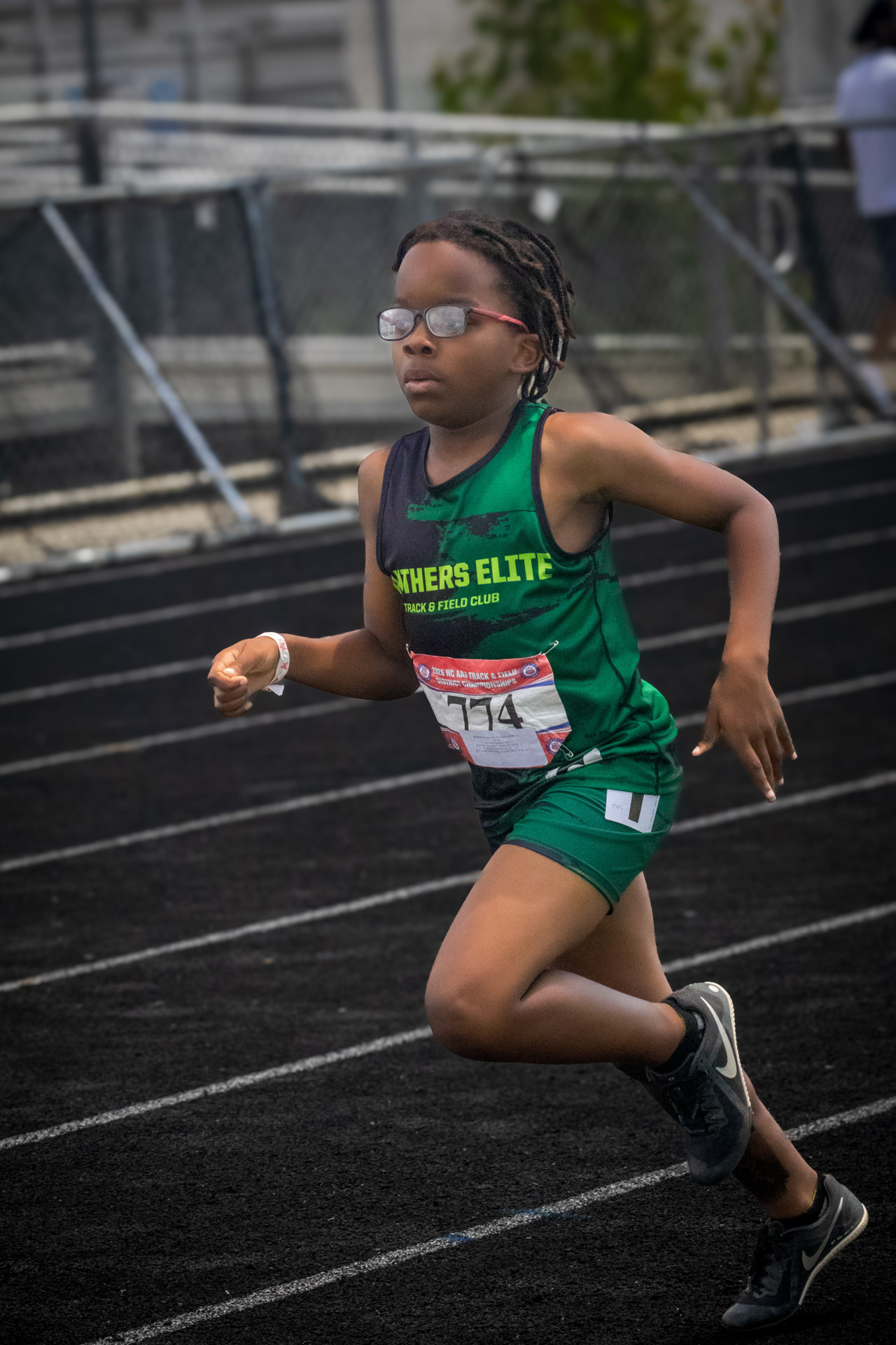 Young female athlete running on track at District Qualifier 2026.