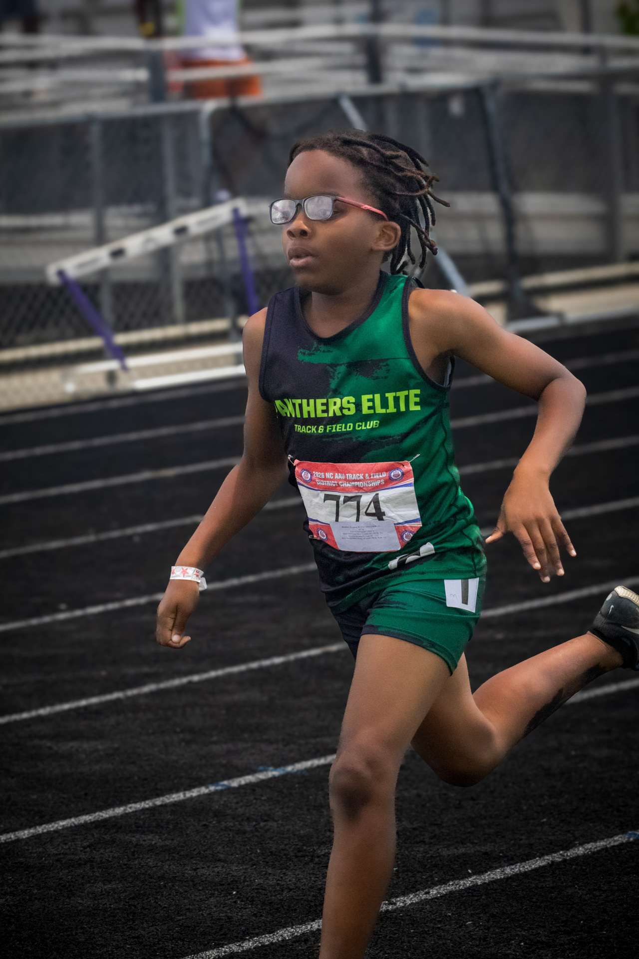 Young female athlete running on track at District Qualifier 2026.