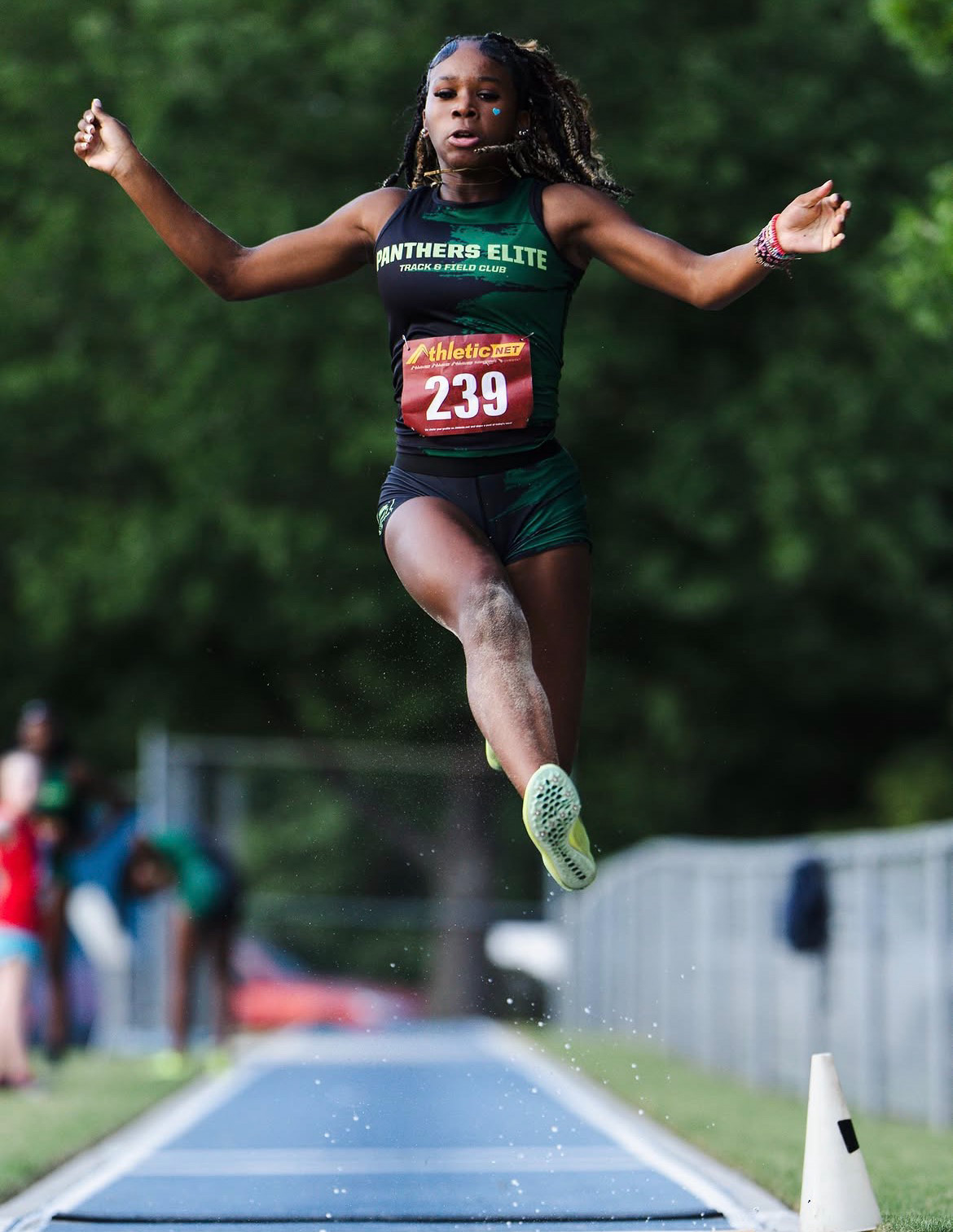 Young female athlete from Panthers Elite in mid-air during long jump event.