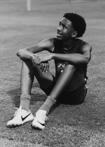 Young male athlete sitting on the track after training or competition.
