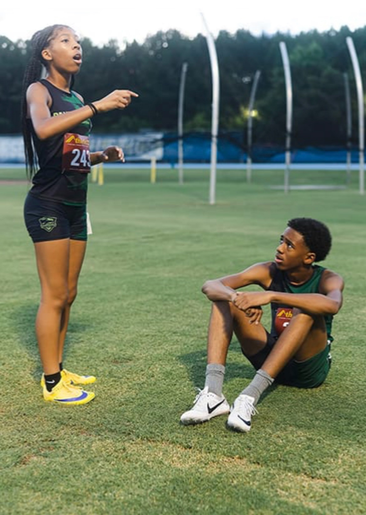 Young female and male athletes at the track field during practice.
