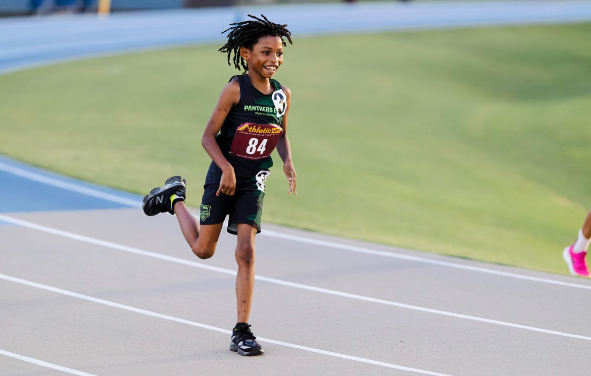 Young female athlete running on track at The Victory Lap 2026 event.