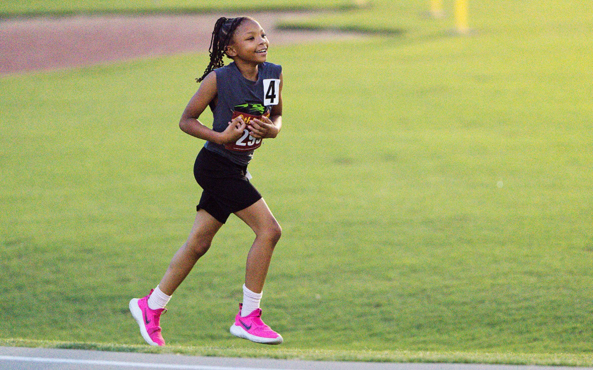 Young girl running on track during a track and field event.